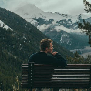 man on a bench in the mountains